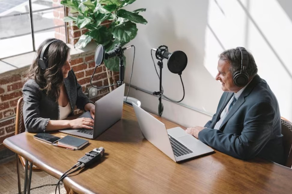 a female broadcaster interviewing an old businessman in a studio