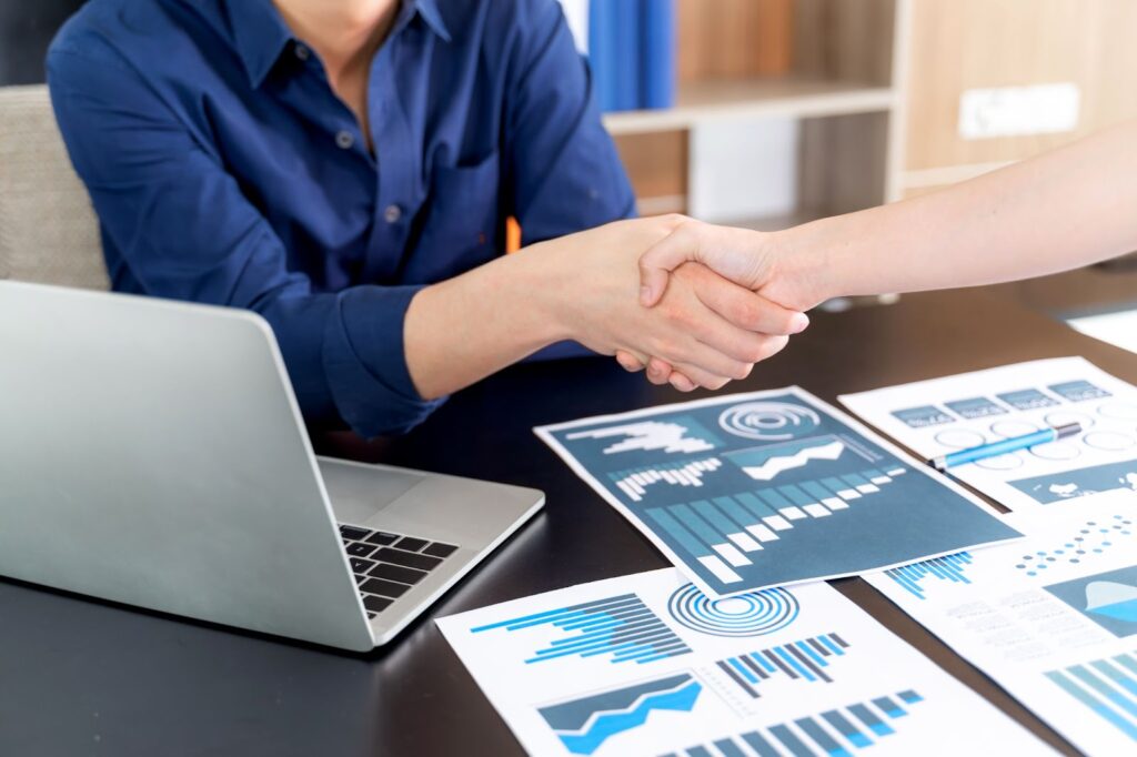 a young man in a blue shirt shaking someone's hand at the office