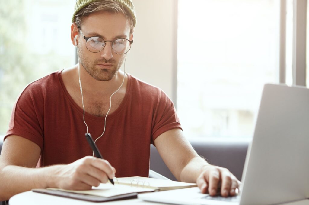 Focused man writes in notebook